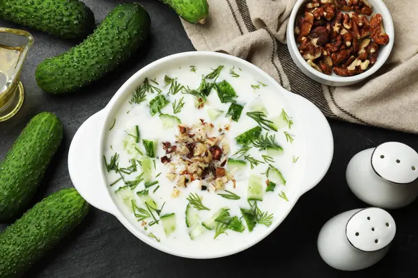 Taze leziz salatalık çorbası ve siyah masa üzerindeki malzemeler.