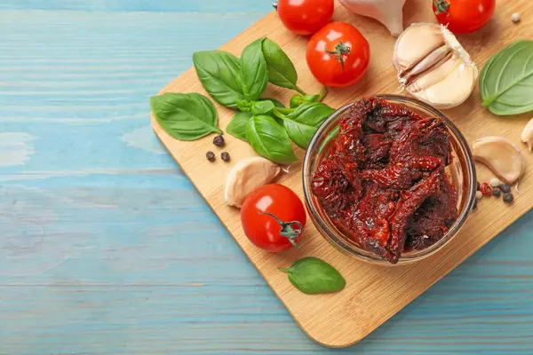 Lezzetli, kurutulmuş domatesler, taze sebzeler, fesleğen ve sarımsak mavi ahşap masa, üst manzara. Metin için boşluk