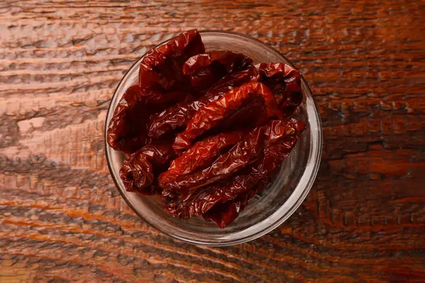 Lezzetli güneş, cam kasede kurutulmuş domatesler, ahşap masa, üst manzara.