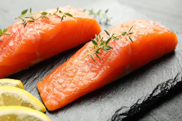 Deniz ürünleri. Somon fileto parçaları, kekik ve limon dilimleri masada, yakın plan.