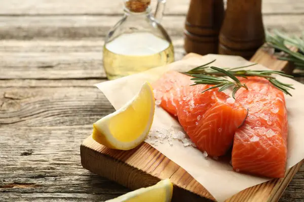 Deniz ürünleri. Somon filetosu, baharat, yağ ve limon dilimleri ahşap masada, yakın plan.