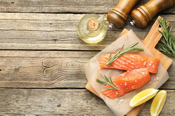 Deniz ürünleri. Somon fileto, baharat, yağ ve limon dilimleri ahşap masada, düz yerde. Metin için boşluk