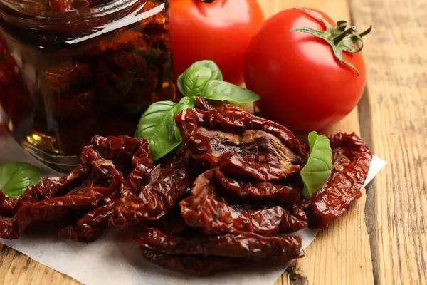 Lezzetli, kurutulmuş domatesler ve taze sebzeler ahşap masada, yakın plan.
