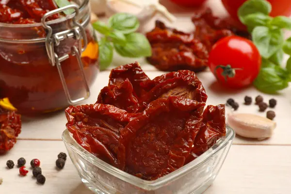 Lezzetli güneşte kurutulmuş domatesler, taze sebzeler ve ahşap masada biberler, yakın plan.