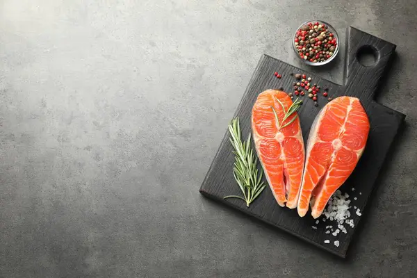 Deniz ürünleri. Çiğ somon bifteği, biberiye ve baharatlar gri masada. Metin için boşluk