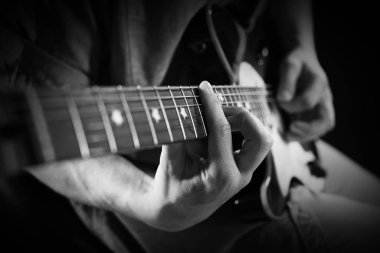 Karanlıkta gitar çalan adam, yakın plan. Siyah ve beyaz etkisi