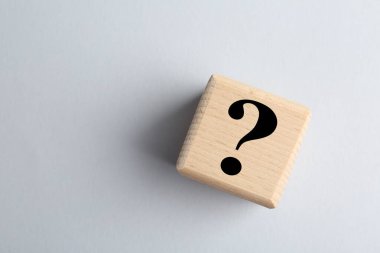 Açık gri arka planda siyah soru işareti olan tahta küp, üst manzara. Metin için boşluk