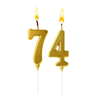 Beyaz arka planda 74 numarayı besteleyen yanan altın pasta mumları. Doğum günü veya diğer özel tarihler için şenlik dekorasyonu