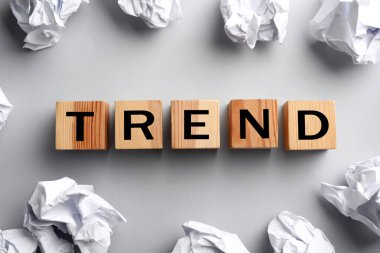 Sözcük Eğilimi harflerle ahşap küplerden ve açık gri arka planda buruşmuş kağıt toplardan oluşur, üstten görünüm