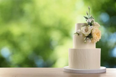 Dışarıdaki ahşap masada çiçeklerle süslenmiş güzel bir düğün pastası. Metin için boşluk