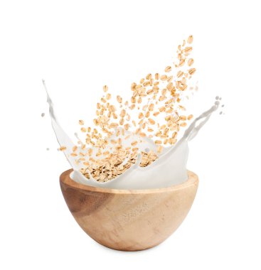 Beyaz arka planda yulaf ve süt fışkırıyor.