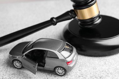 Motorlu taşıt kazası yasası. Gri arkaplanda Gavel ve araba modeli