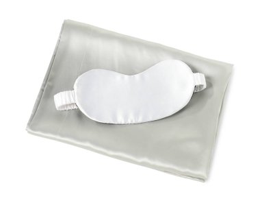 Beyaz arka planda ipek çarşaflar ve uyku maskesi.