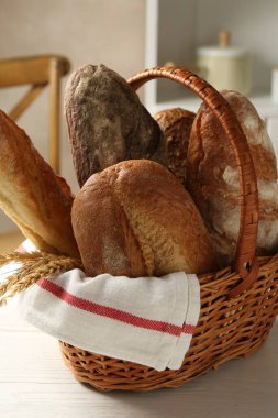 Farklı somunlar taze ekmek ve çiviler sepetin içinde beyaz ahşap masa, yakın plan