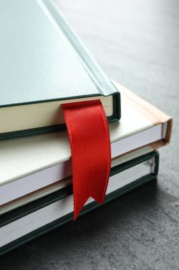 Kırmızı kurdele yer imi ve gri desenli masa üzerindeki renkli kitap, yakın plan.