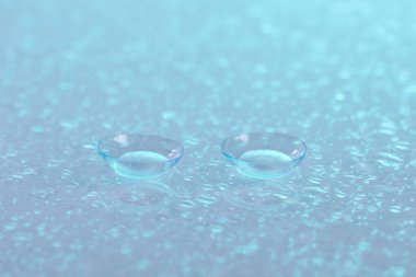 Renkli ayna yüzeyine kontak lens ve su damlaları, yakın plan.