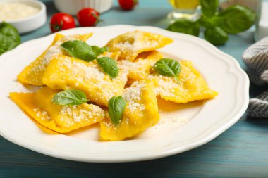 Peynirli ve fesleğenli leziz ravioli açık mavi ahşap masa, yakın plan.