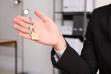 Ev anahtarı olan bir emlakçı, yakın plan.