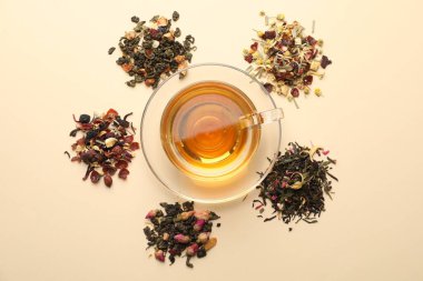 Cam fincanda nefis bitki çayı ve bej arka planda kuru yapraklar.