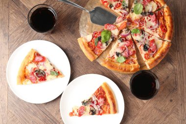 Tahta masada servis edilen ince tütsülenmiş sosisli lezzetli pizza dilimleri.