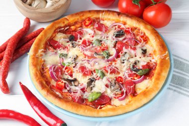 İnce tütsülenmiş sosis ve malzemelerle dolu leziz bir pizza, yakın plan.