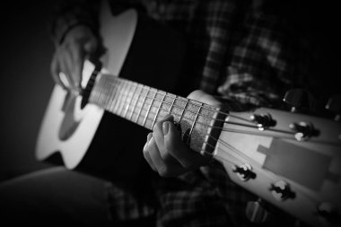 Karanlıkta gitar çalan kadın, yakın plan. Siyah ve beyaz etkisi