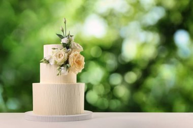 Dışarıdaki ahşap masada çiçeklerle süslenmiş güzel bir düğün pastası. Metin için boşluk