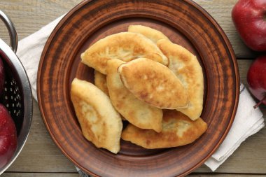 Lezzetli kızarmış pirizky (doldurulmuş turtalar) ahşap masa üzerinde elmalar, düz yatar