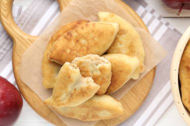 Lezzetli kızarmış pirizky (doldurulmuş turtalar) ve beyaz ahşap masa üzerinde elmalar, düz yatıyordu.