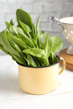 Taze kuş yaprakları kasede ve kevgir masada, yakın plan.