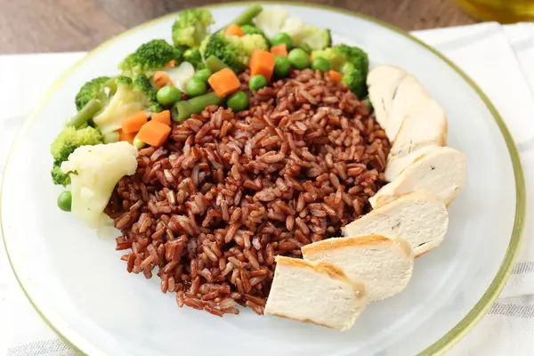 Tahta masada servis edilen tavuk ve sebzeli lezzetli kahverengi pirinç.