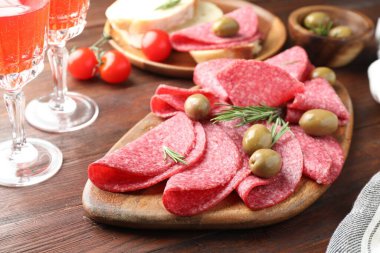 Ahşap masada servis edilen zeytinli ve biberiyeli lezzetli sosisler.