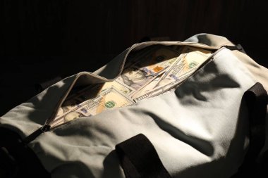 Siyah arkaplanda dolar banknotları olan çanta, yakın plan.