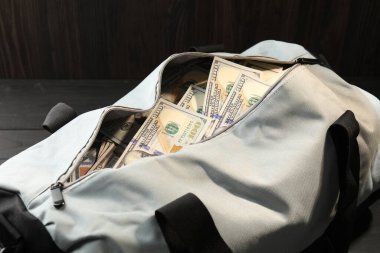 Tahta masanın üzerinde dolar banknotları olan çanta, yakın plan.