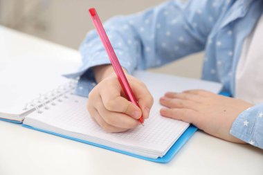 Küçük kız ev ödevlerini içeride yapıyor, yakın plan.