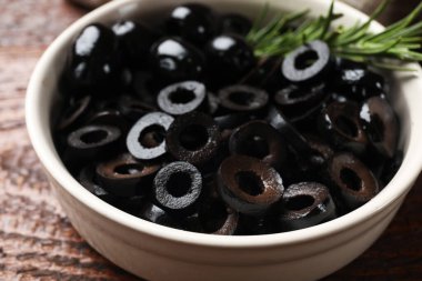 Lezzetli marine edilmiş zeytin halkaları ve biberiye ahşap masada, yakın plan.