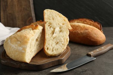 Farklı türde taze ekmek ve bıçak koyu dokulu masa, yakın plan.