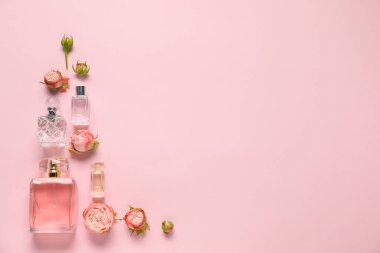 Parfüm şişeleri ve pembe arka planda güzel çiçekler. Metin için boşluk