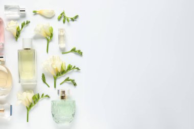 Parfüm şişeleri ve beyaz arka planda güzel çiçekler. Metin için boşluk