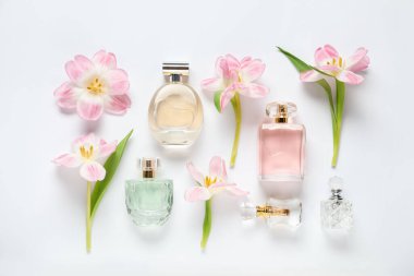 Parfüm şişeleri ve beyaz arka planda güzel çiçekler.