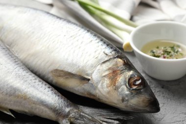 Gri masada tuzlanmış ringa balıkları ve baharatlar, yakın plan.