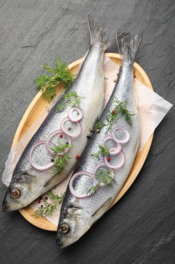 Lezzetli ringa balıkları, siyah masa üzerinde baharatlar, üst manzara.