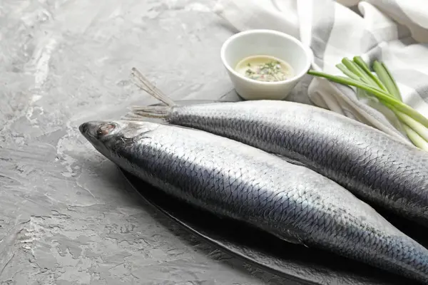 Gri masada tuzlanmış ringa balıkları ve baharatlar, yakın plan. Metin için boşluk