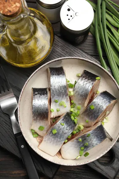 Lezzetli ringa balıkları. Yeşil soğanlı. Siyah ahşap masada servis ediliyor.