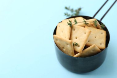 Açık mavi arka planda lezzetli tuzlu krakerler ve kekik, yakın plan. Metin için boşluk