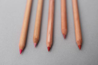 Açık gri arkaplanda pek çok farklı dudak kalemi, yakın plan