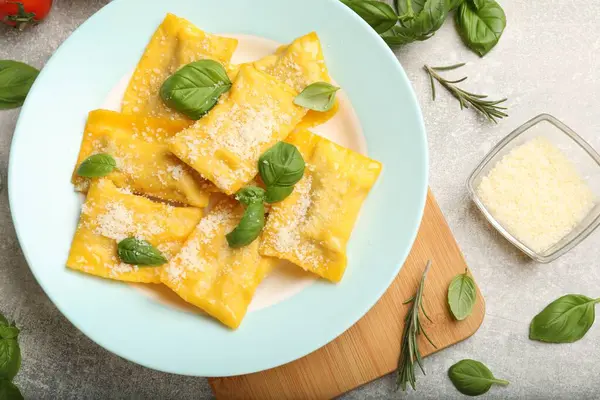 Peynirli ve fesleğenli lezzetli ravioli gri masada servis edilir.