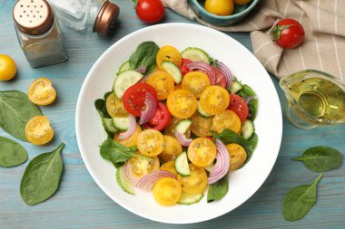 Açık mavi ahşap masada servis edilen yeşil domatesli taze salata.