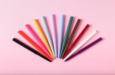 Pembe arka planda renkli göz kalemleri, düz yatış