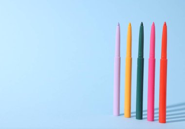 Açık mavi arka planda renkli göz kalemleri. Metin için boşluk